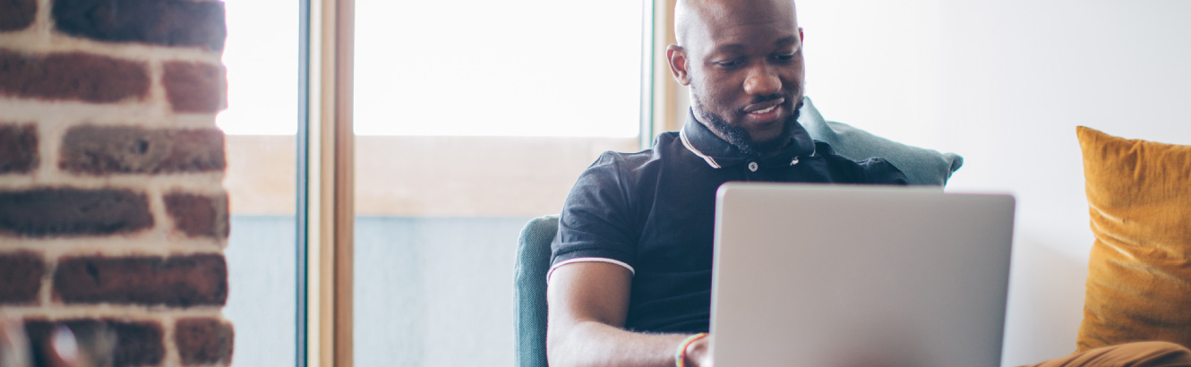 A man lounging at home on his laptop.